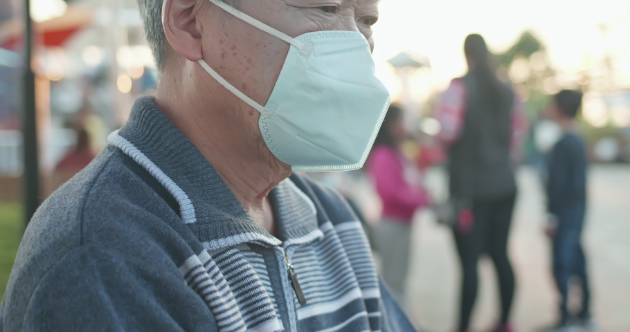 asian old man think something and wear protective n95 mask because of transmissible infectious diseases or air pollution outdoor in the crowd