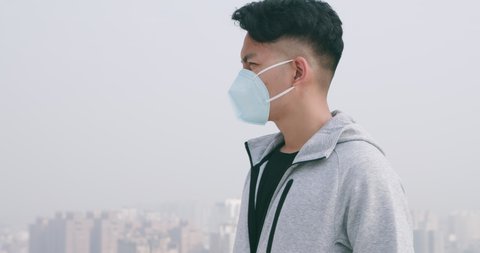 slow motion back view of asian man look something and wears protective n95 mask against air pollution or transmissible infectious diseases in the city