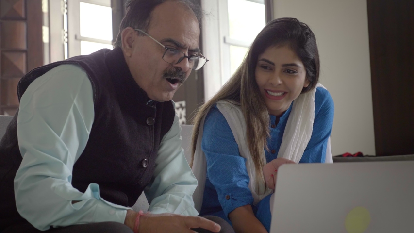 Smiling Daughter teaching her father how to make payment using online banking on a laptop. A beautiful and traditional young woman showing an elderly man how to shop buy things online.  Royalty-Free Stock Footage #1047184993