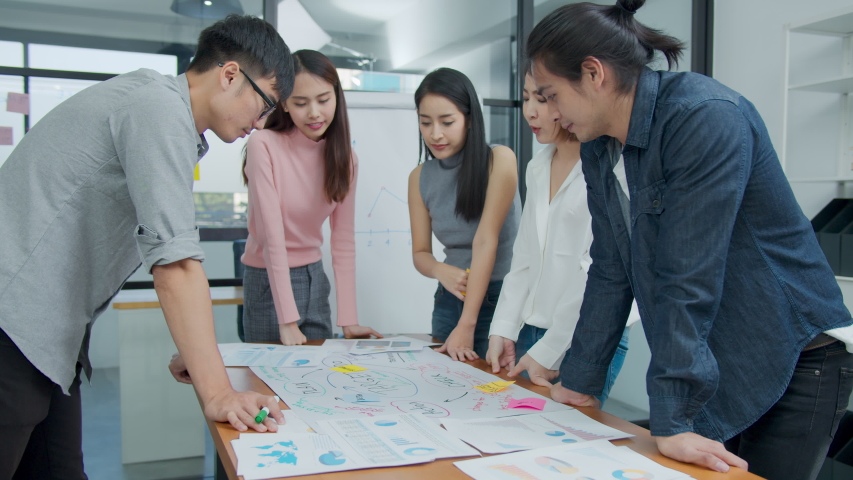 Slow motion : Group of asian creative employee standing and brainstorming stategy plan in happy workshop at creative workplace. Effective meeting, productive workshop and synergy business concept Royalty-Free Stock Footage #1047193606