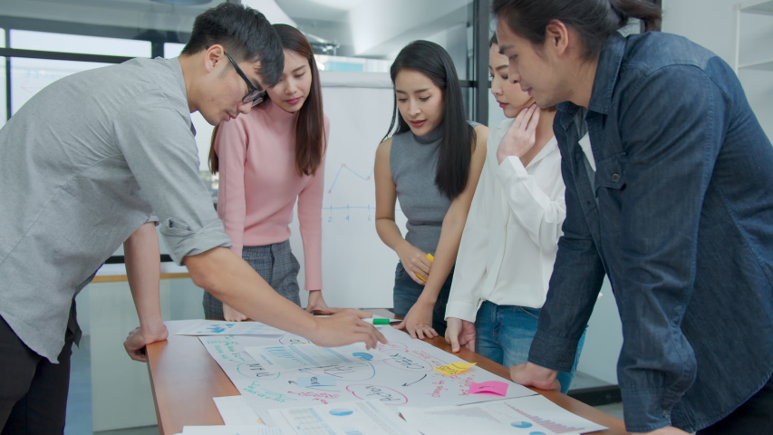 Slow motion : Group of asian creative employee standing and brainstorming stategy plan in happy workshop at creative workplace. Effective meeting, productive workshop and synergy business concept Royalty-Free Stock Footage #1047193606