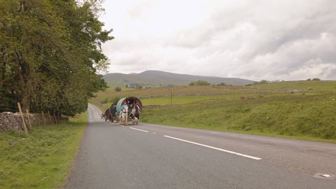 Kirkby Stephen , Cumbria / United Kingdom (UK) - 05 30 2019: Horses pulling traditional gypsy caravans up a hill on a country road