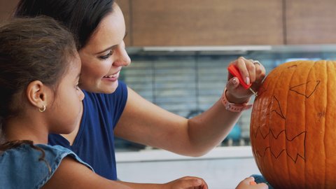 Mother And Daughter Carving Halloween Lantern From Pumpkin At Home Vídeo Stock