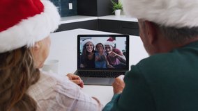 Multi-generation hispanic family wearing santa hats with laptop having video chat at christmas - shot in slow motion