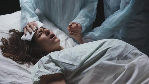 Exhausted tired woman in labor gives birth to child, maternity ward pushing hard, young mother screams writhing in pain during childbirth in hospital, professional medical care of doctors, pregnancy
