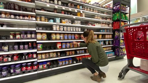 Santa Rosa , CA / United States - 10 22 2019: Woman trying to pick out peanut butter at her local Target store