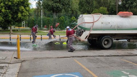 San Andres Cholula , Puebla / Mexico - 10 21 2019: Cholula/Mexico: 10-21-2019: City crew cleaning the street with a water pipe