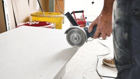 Workman cutting ceramic tiles with handy machine at the construction site indoors