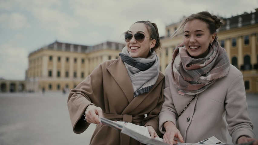 Two young girls tourists look at the map, have fun, laugh and argue. Vienna, Austria (Europe).