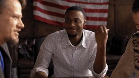 Cheerful Businessmen Make Connections Communicate In The Interior Of A Loft-Style Office, Multiethnic Group African Guy And Two Caucasians Laugh Together During A Meeting, American Flag On Background - Powered by Shutterstock - Get 15% off with code: PIKWIZARD15