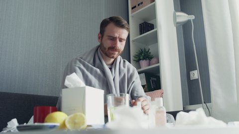 Sick man pouring medication or antipyretic syrup to spoon and drinking it