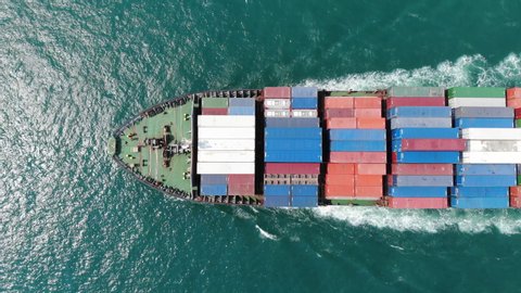 Aerial of smart cargo ship carrying container and running for export  goods  from  cargo yard port to other ocean concept freight shipping ship on blue sky background.