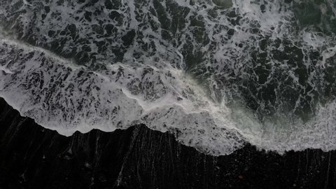 Atlantic Ocean, strong surf on lava rock and black sand with white spume, wave study, vertical view from above