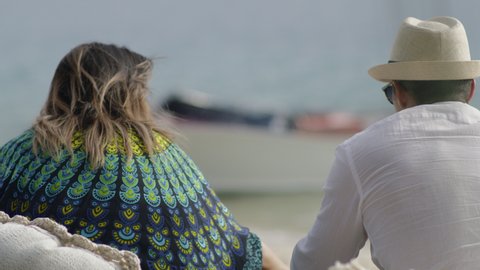 Good looking young adult friends picnic while looking out onto dingy boat on a sandy beach in Australia. Closeup to medium shot on 4K RED camera.