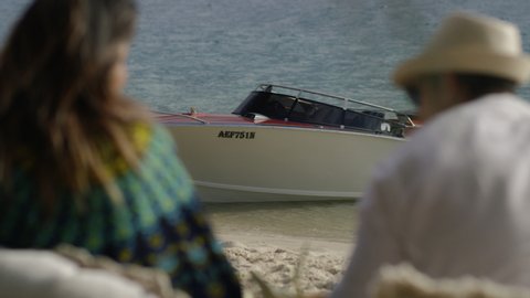 Fun millennial friends look out onto boat on a sandy beach under sunny blue sky in Australia. Closeup to medium shot on 4K RED camera.