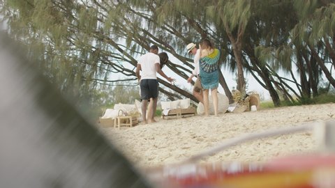 Hot millennials get off boat and go to sandy beach under sunny blue sky in Australia. Medium to wide shot on 4K RED camera.