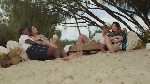 Two couples sitting at a picnic area quietly and happily on the beach in Australia with soft day lighting. Wide shot on 4k RED camera.