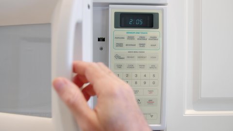 Using a digital keypad to set the microwave oven power level and microwaving time for cooking or reheating. Selecting temperature and cooking timer duration on home kitchen appliance.