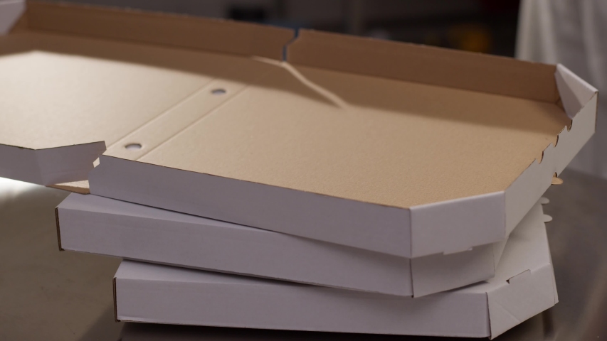 Close up hands professional chef puts just now cooked pizza from oven inside a pizza box ready for delivery recipe take-out meat hot eat take-away box slow motion