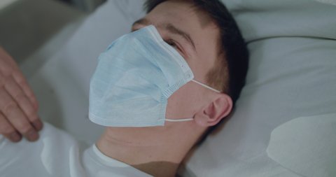 Portrait of ill, dying from virus man in medical mask lying on bed, doctor explaining him how to breathe. Slowly in 4K