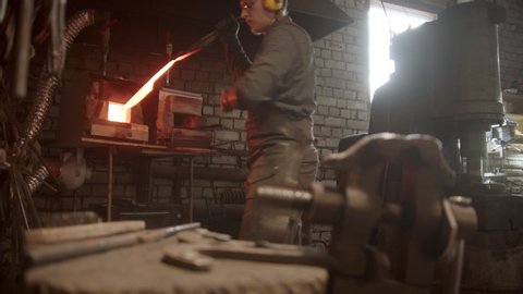 A man blacksmith forging a knife - putting the sample between the clamps