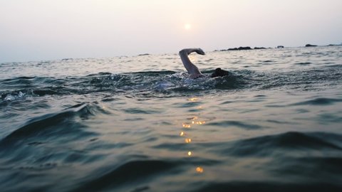 woman swimmer athlete at her morning swimming freestyle workout at sunrise in open sea. Athletic Girl preparing for triathlon race in open water