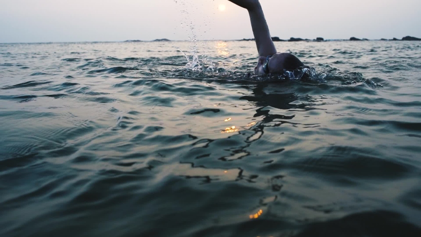 young woman swimmer athlete finish her morning swimming freestyle workout at sunrise in open sea. Girl preparing for triathlon race in open water Royalty-Free Stock Footage #1047256513
