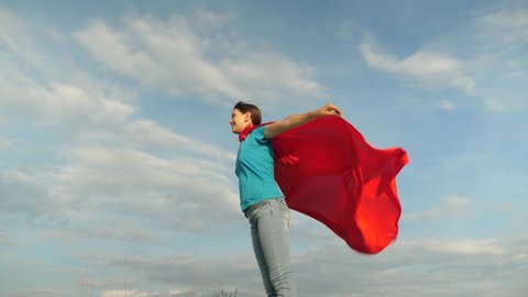Child plays in a red cape, dream of becoming a hero Superwoman. Slow motion. 