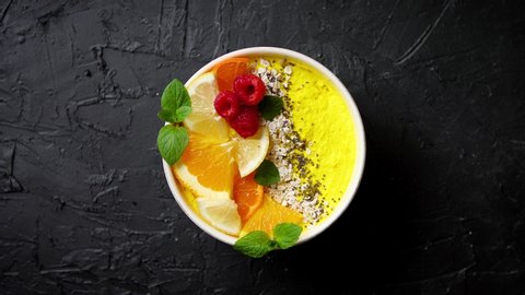 Tasty orange fresh smoothie or yogurt served in bowl. With fresh raspberries, orange slices, chia seeds, oat. Placed on stone table. With copy space.