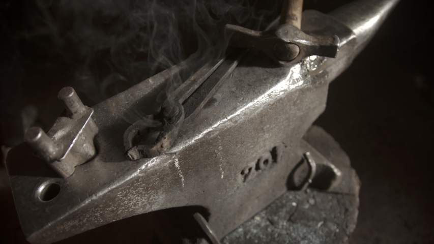A blacksmith instruments on the anvil covered in steam