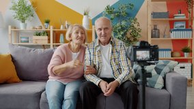 Elderly people bloggers are recording video with camera talking gesturing making blog content at home. Modern technology, retirement and occupation concept.
