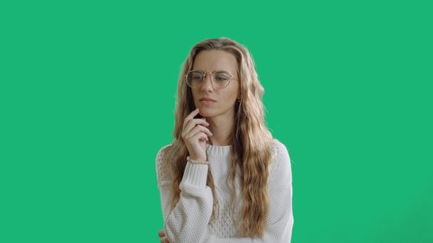 Hmm. Suspicious thoughtful young female looking up, keeping hand on her face as if trying hard to remember something important. A confused woman on a green screen chroma key background