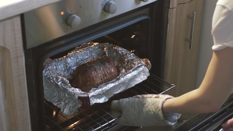 Meatloaf in the oven for roasting, Woman open the oven at the kitchen, meat recipes, grilling.