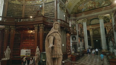 VIENNA AUSTRIA Sep 15. 2019 AUSTRIAN NATIONAL LIBRARY moving forward shot through the baroque state hall to statue of emperor Kaiser Karl VI tourist attraction for sightseeing