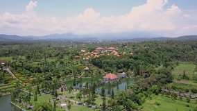 Aerial view of amazing balinese village. Tracking shot of beautiful Bali island. Drone shot of asian temple by the lake. Indonesia