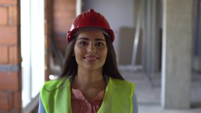 Female engineer or architect walking in a construction site portrait. Handheld video. 
