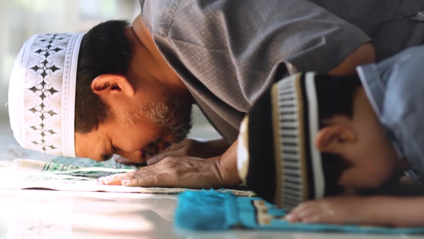 Shot of Religious Asian Muslim Man teaching his little son to pray to God in Sujud position.For praise and glorify Allah.Innocent child has been practicing by father.Concept of Muslim people praying. Royalty-Free Stock Footage #1047280585