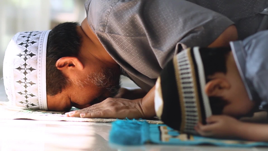 Shot of Religious Asian Muslim Man teaching his little son to pray to God in Sujud position.For praise and glorify Allah.Innocent child has been practicing by father.Concept of Muslim people praying. | Shutterstock HD Video #1047280585