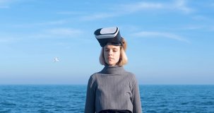 Young handsome female  with virtual reality glasses outdoor on the beach against sunny blue sky