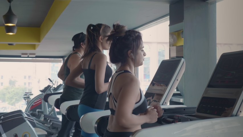 A group of fit and attractive athletes using treadmill to workout in a modern gym. Three youngsters running and warming up during intense cross fit cardio training session in a fitness studio. Royalty-Free Stock Footage #1047286192