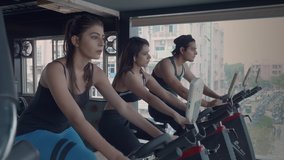 A movement shot of group of attractive youngsters training on stationary exercise bike. Male and female gym enthusiasts working out warming up on bicycles during cardio work out in a fitness studio. - Powered by Shutterstock - Get 15% off with code: PIKWIZARD15