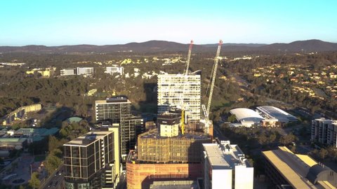 CANBERRA, AUSTRALIA – FEBRUARY 26, 2020: Aerial pullback reveal shot of Belconnen Town Centre showing tower cranes and construction during late afternoon in Canberra, the capital of Australia