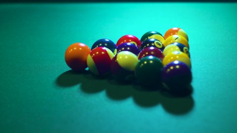 Multi-colored billiard balls on a billiard table with green cloth roll in different directions from a strong blow with a cue. Gambling snooker. Entertaining leisure at the hotel. Close-up.