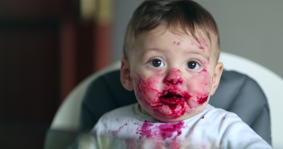 Feeding cute messy happy baby toddler smiling covered with red sauce fruit. Royalty-Free Stock Footage #1047304147