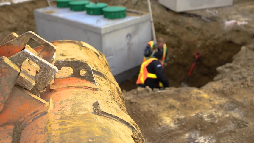 Close up footage in shallow focus as builders install concrete septic tank sewer chambers on a construction site, using level staff to check heights Royalty-Free Stock Footage #1047304333