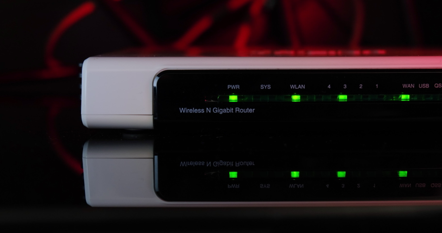 Wireless N Gigabit Router on reflective glass table - front close up view, with red light in the back.