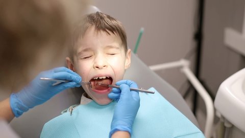 The child is afraid of the dentist, little boy visiting the dentist and looking scared