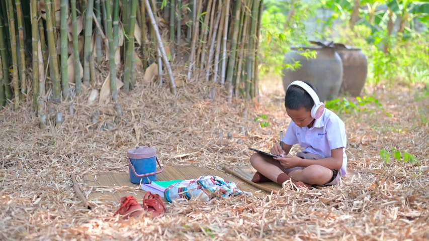 Asian students are working while listening to music happily in the garden.