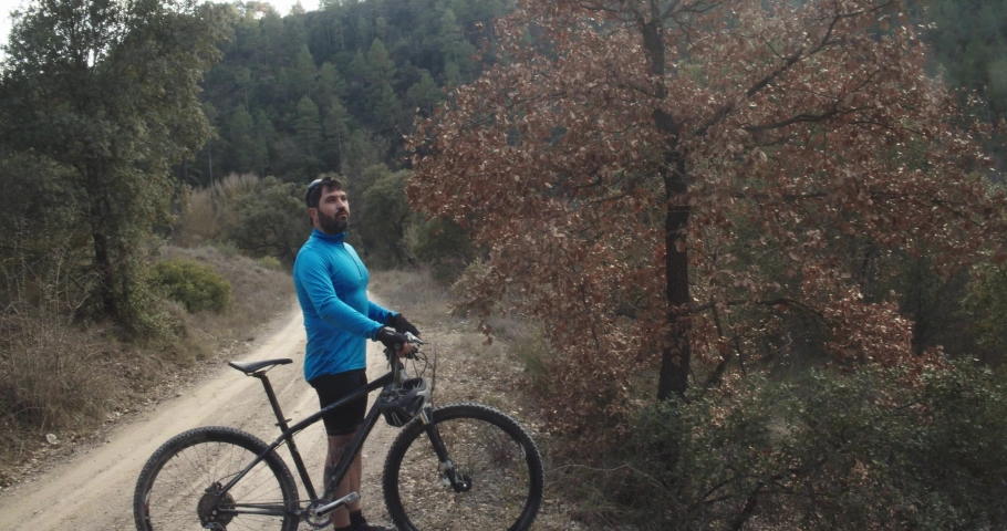 Mountain biker through a forest putting on his helmet
