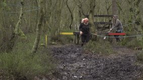 Two women running through a mud run / assault / obstacle course. They are racing through the muddy track, competing - Stock 4K Video clip footage